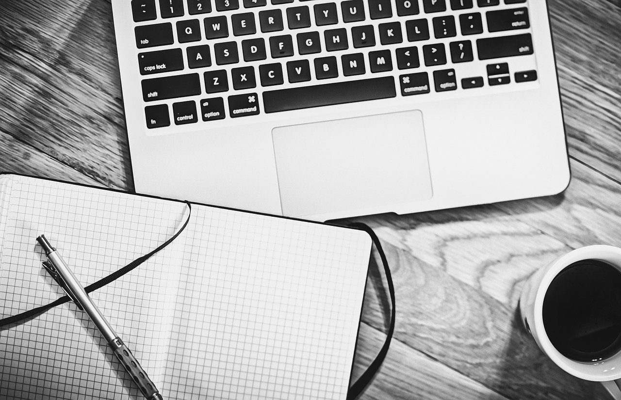 Laptop, Notizbuch und Kaffeetasse