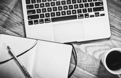 Laptop, Notizbuch und Kaffeetasse
