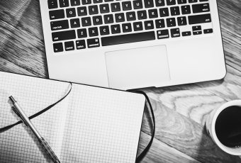 Laptop, Notizbuch und Kaffeetasse