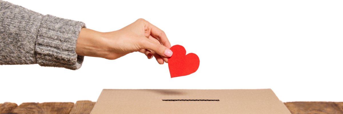 Hand, die Herz in Karton wirft