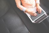 Weibliche Person mit Laptop auf dem Schoß von schräg oben fotografiert