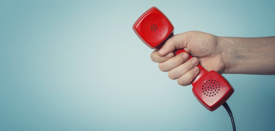 Roter Telefonhörer in der Hand