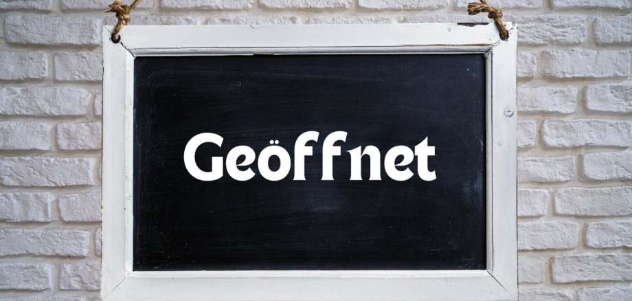 Tafel an einer Steinmauer mit der Aufschrift geöffnet