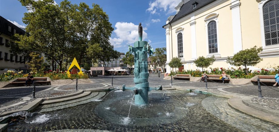 Brunnen auf einem Platz mit Kirche im Hintergrund