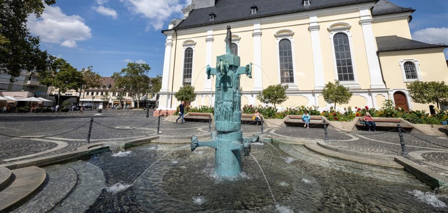 Brunnen auf einem Platz mit Kirche im Hintergrund