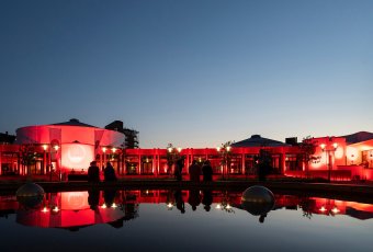 Beleuchtetes Gebäude bei Nacht, Spiegelung im Brunnen davor