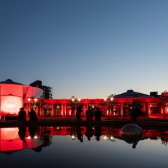 Beleuchtetes Gebäude bei Nacht, Spiegelung im Brunnen davor