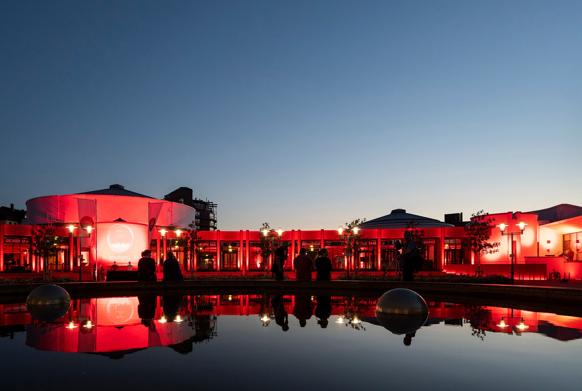 Beleuchtetes Gebäude bei Nacht, Spiegelung im Brunnen davor