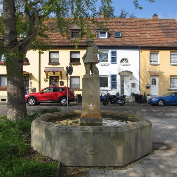 Wohnhaus mit Brunnen im Vordergrund