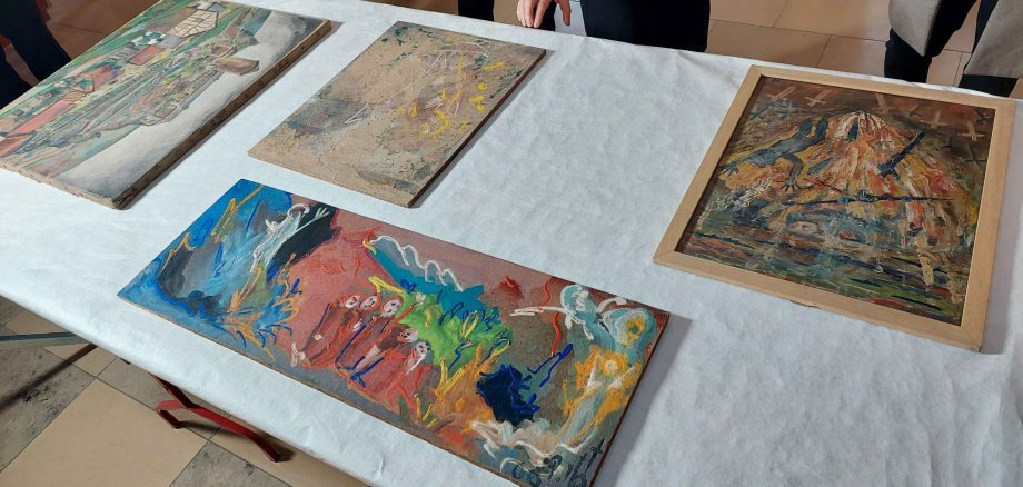 Auf dem Tisch ausgebreitet werden die beschädigten Gemälde aus dem Ahrtal nach ihrer Annahme zur Restaurierung das erste Mal  begutachtet