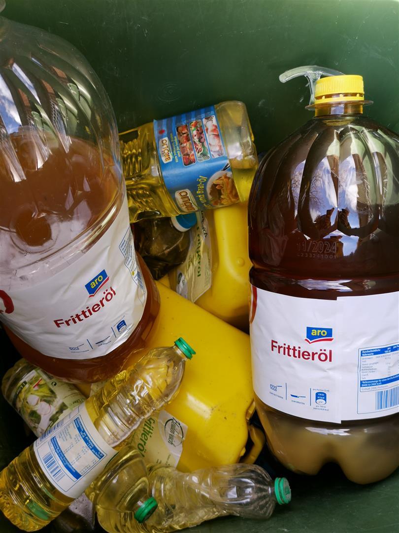 Mehrere Plastikgebinde gefüllt mit gebrauchtem Speisefett in der 240L-Speisefetttonne.