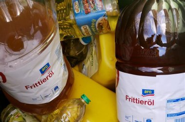 Mehrere Plastikgebinde gefüllt mit gebrauchtem Speisefett in der 240L-Speisefetttonne.