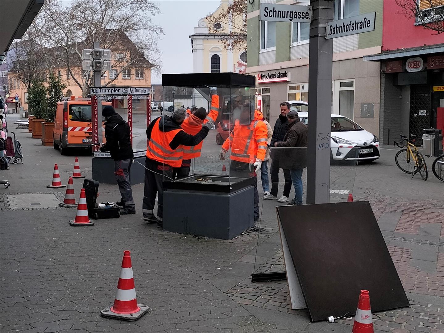 Mehrere Personen montieren Schaukästen ab.