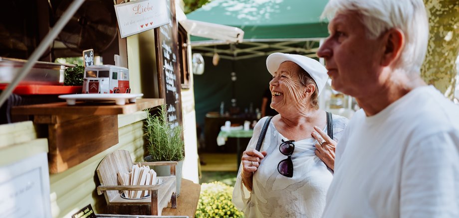 Menschen lesen eine Tafel an einem Foodtruck