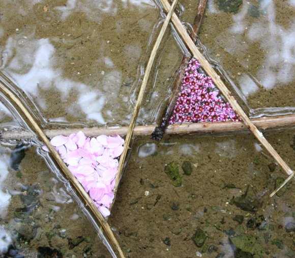Zu sehen ist ein Objekt aus Bambusstäben im Wasser