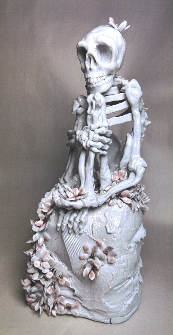 Kunstwerk Death with flower Zu sehen ist eine Porzellanfigut die ein Skelett darstellt mit Blumen verziert.