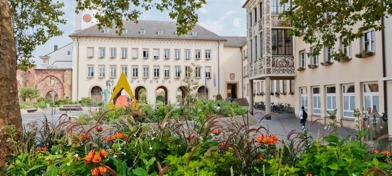 Blumenbeete vor einem Platz und einem Gebäude mit Arkaden