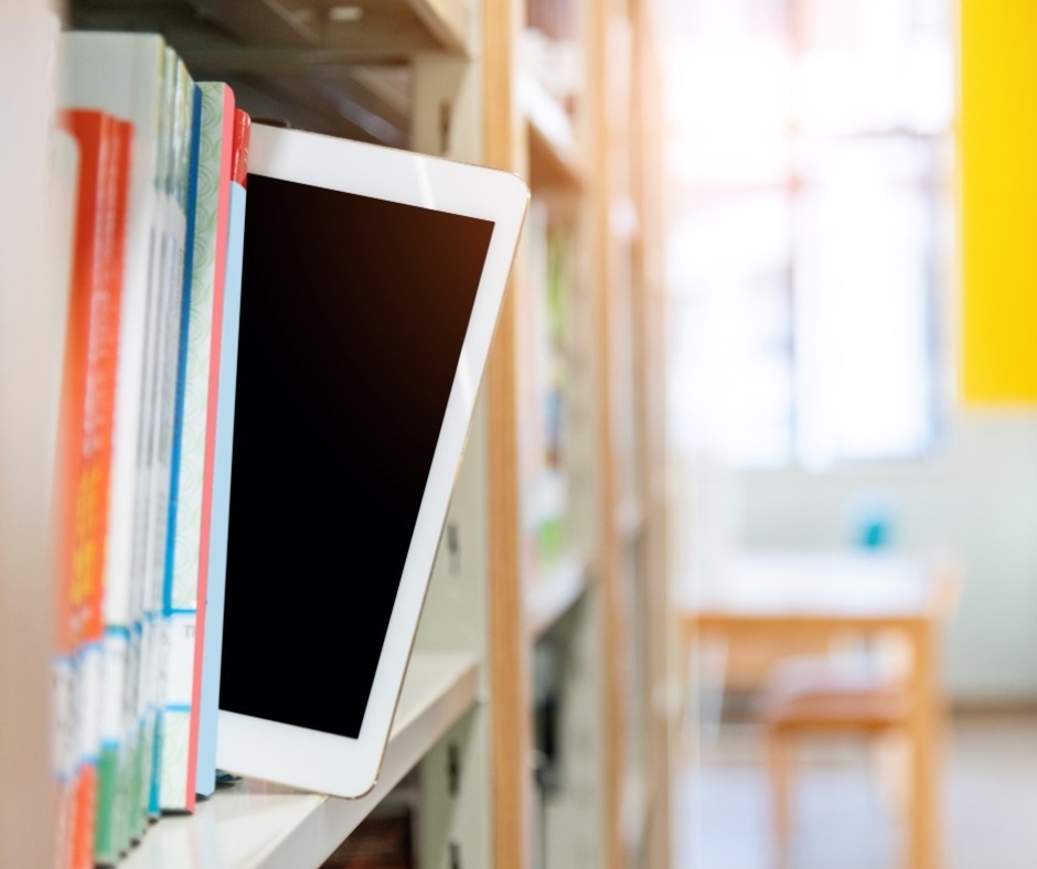 Digitale Angebote Tablet steckt zwischen Büchern in einem Regal und schaut etwas heraus