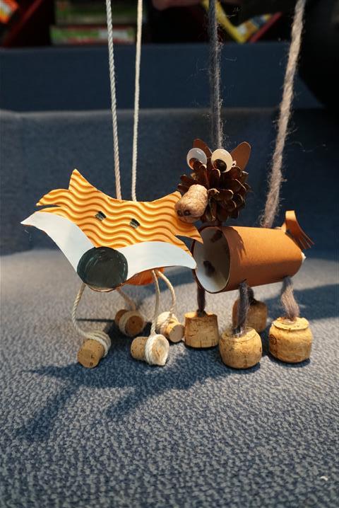 Vorhang auf! Marionetten für ein Puppentheater gestalten der Hintergrund ist blau. Davor ist eine Marionette als Fuchs und ein Wildschwein. An den zwei Tieren hängen Schnüre.