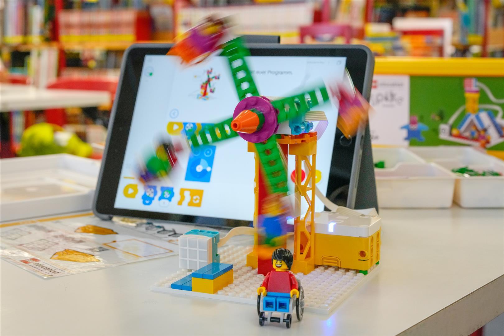 Bauen und Programmieren mit LEGO SPIKE Essential Ein Tablet steht auf dem Tisch und im Vordergrund ist mit LEGO SPIKE ein Windrad gebaut das sich dreht