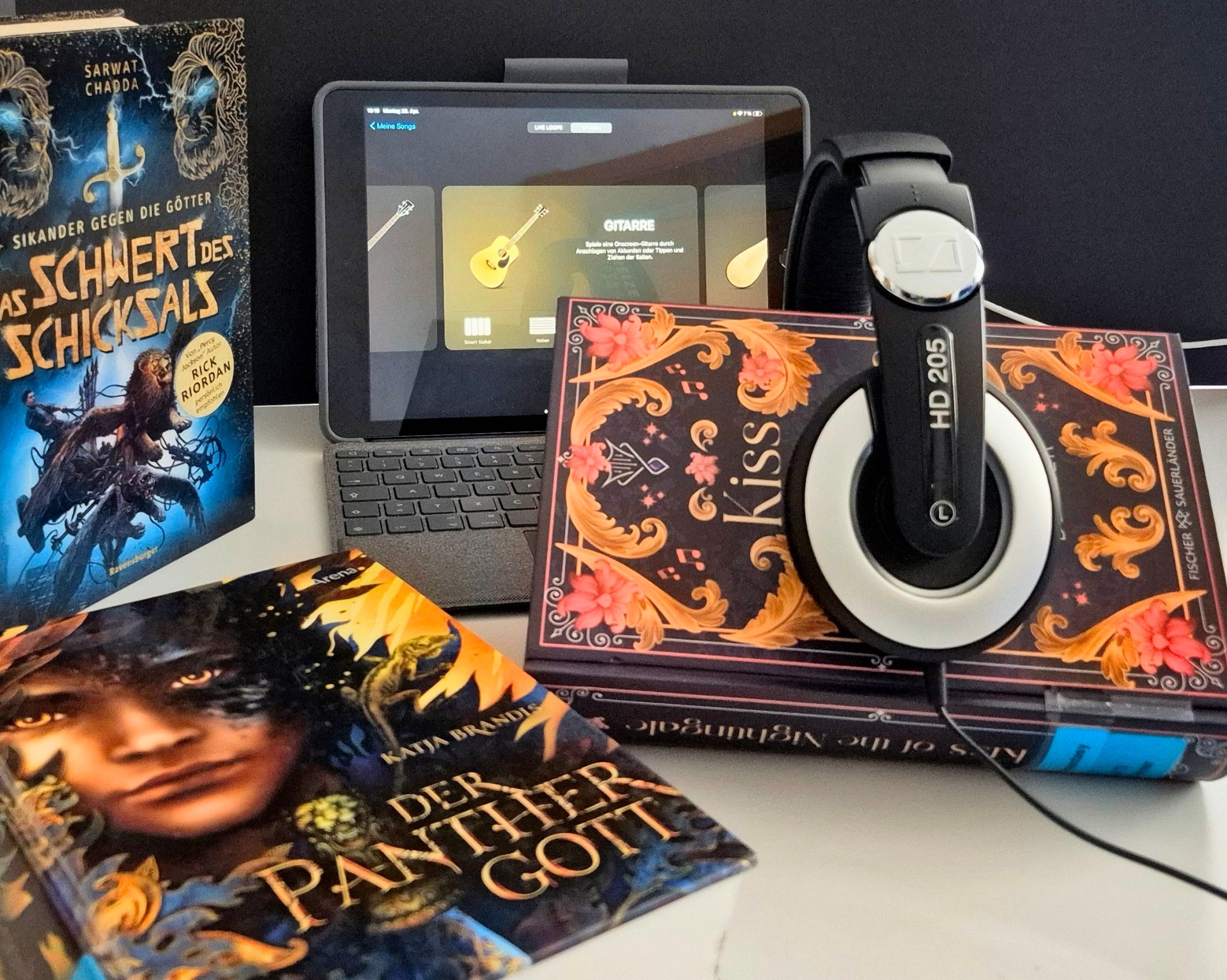 Ein Buch mit Kopfhörern. Dahinter ein Tablet.