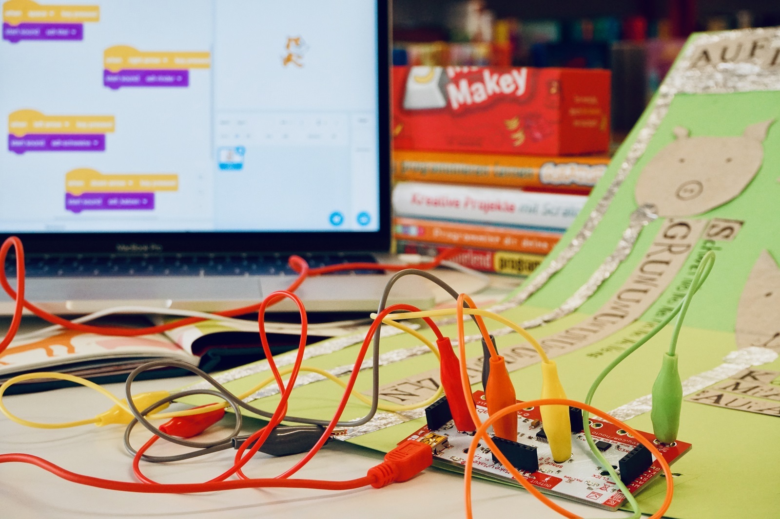 MakeyMakey Im Vordergrund Kabel und Lüsterklemmen, im Hintergrund ein PC