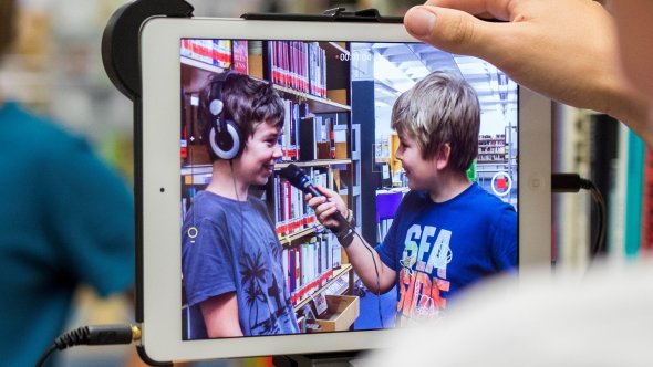 Podcast aufnehmen Zwei Jungs führen mit Mikrofon und Tablet ein Interview.