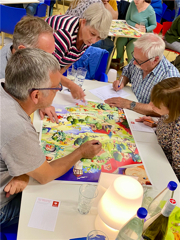 fünf Personen beugen sich über ein Bild und betrachten es suchend