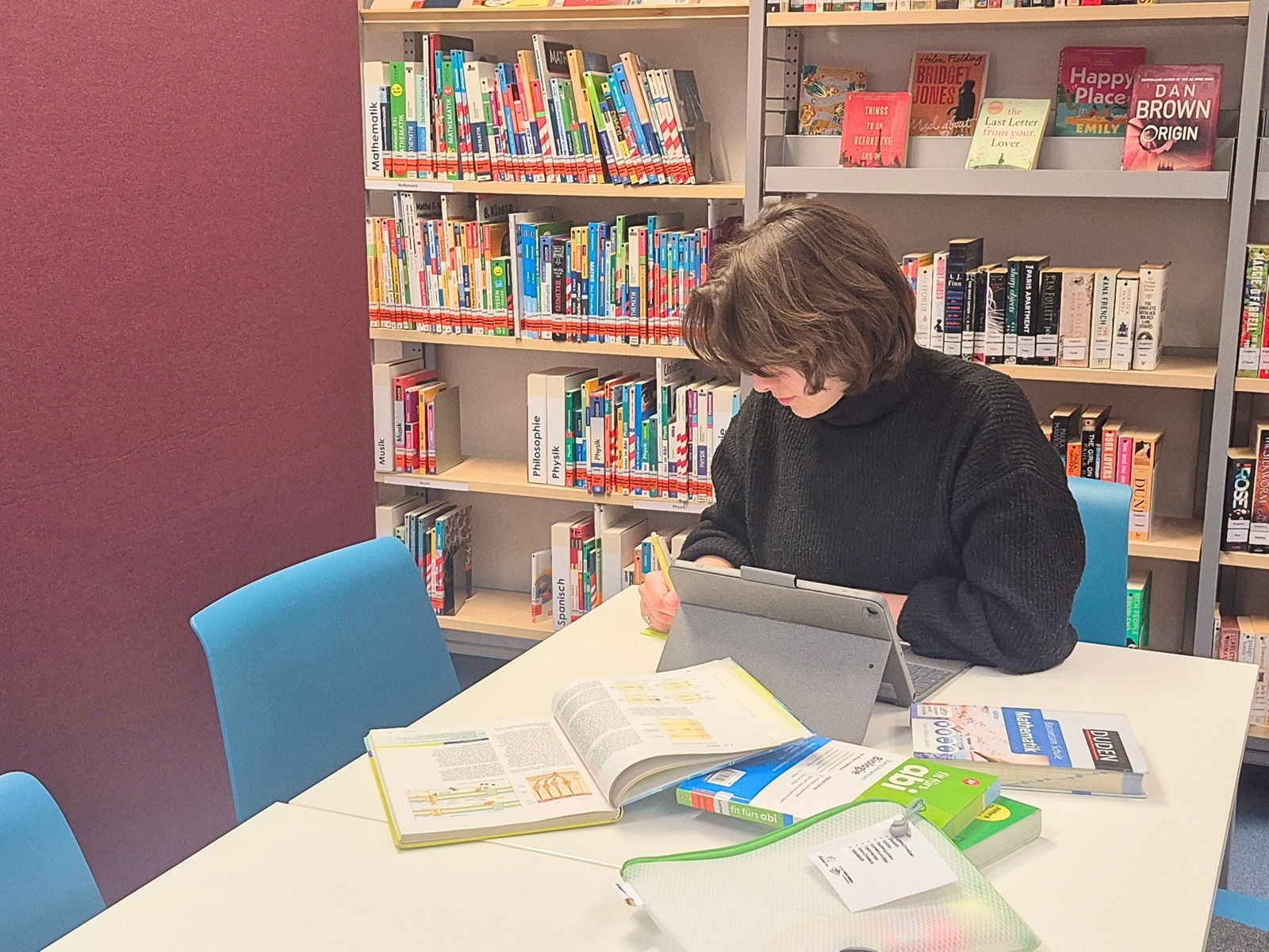 Junge Frau an einem Tisch mit Büchern.