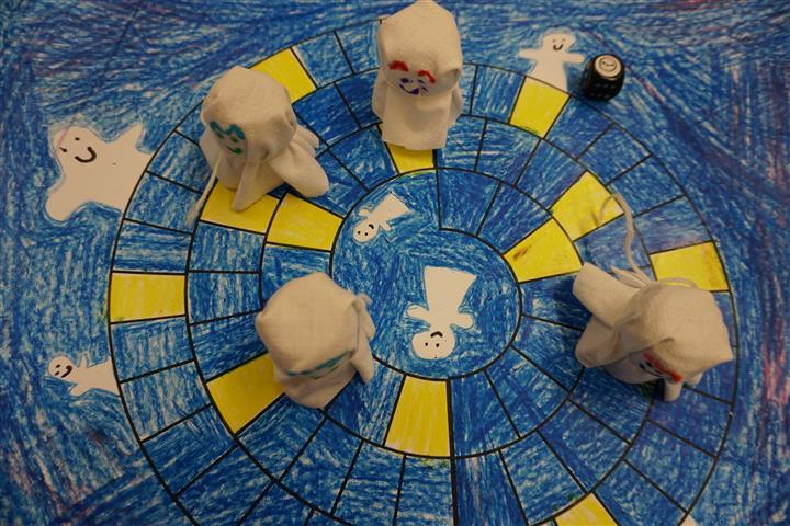 Spiel ab! Blick von oben auf ein selbst gemaltes Spielfeld mit 4 selbstgebastelten Geister-Spielfiguren