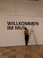 Aufbau der Ausstellung 14: Bernd Mohr bringt die Klebebuchstaben mit einem Rakel an der Wand an.
