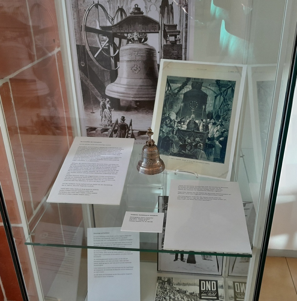 Eine Vitrine der Ausstellung "Glockenguss in Frankenthal" zeigt die Geschichte der in Frankenthal gegossenen Kaiserglocke anhand von Objekten, Fotografien und Texten