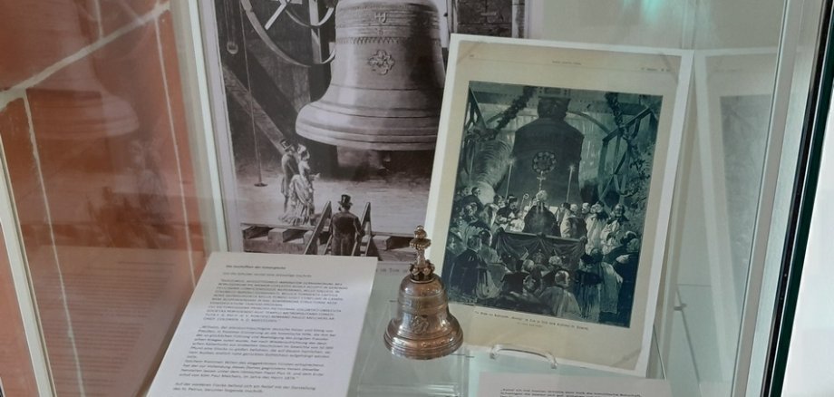 Eine Vitrine der Ausstellung "Glockenguss in Frankenthal" zeigt die Geschichte der in Frankenthal gegossenen Kaiserglocke anhand von Objekten, Fotografien und Texten