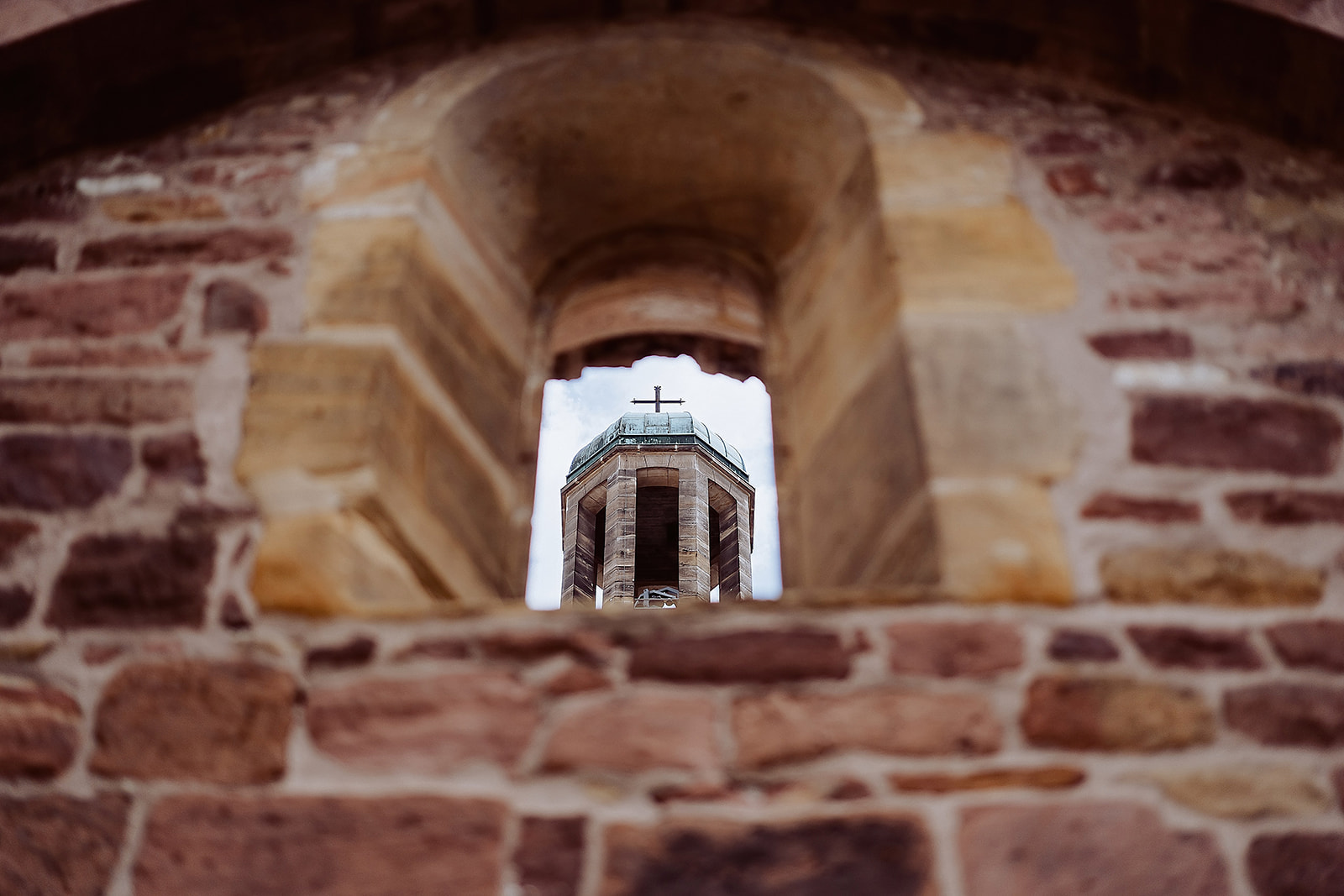 Frankenthal Historische Steinmauer mit Fenster, durch das ein Kirchturm zu sehen ist.