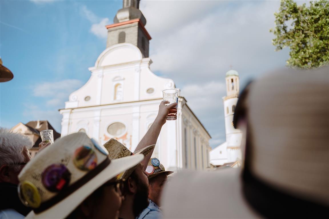 Menschen mit Strohhüten vor einer Kirche
