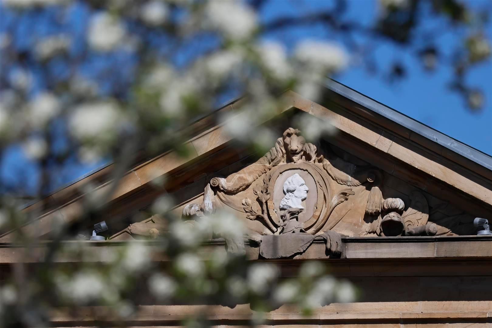 Blühender Baum vor Tor mit Löwe aus Stein und Bildnis des Kurfürsten Carl-Theodor