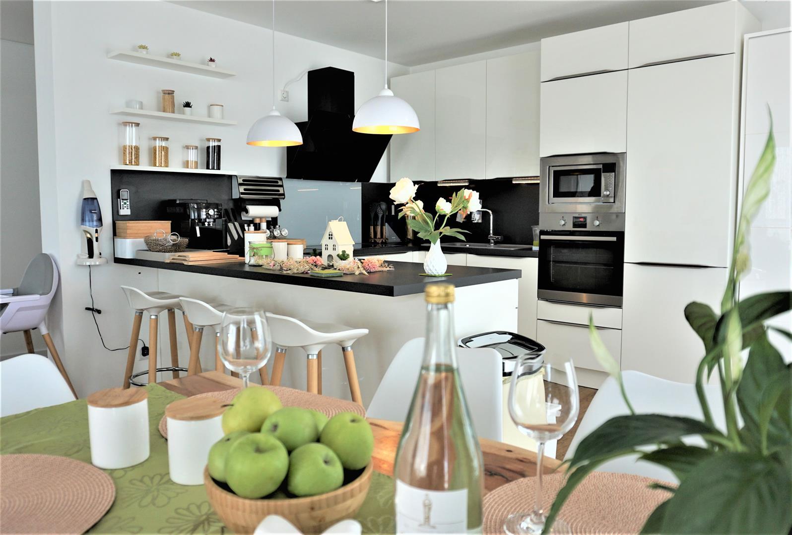 Esstisch mit Äpfeln vor Küchentresen mit Stühlen