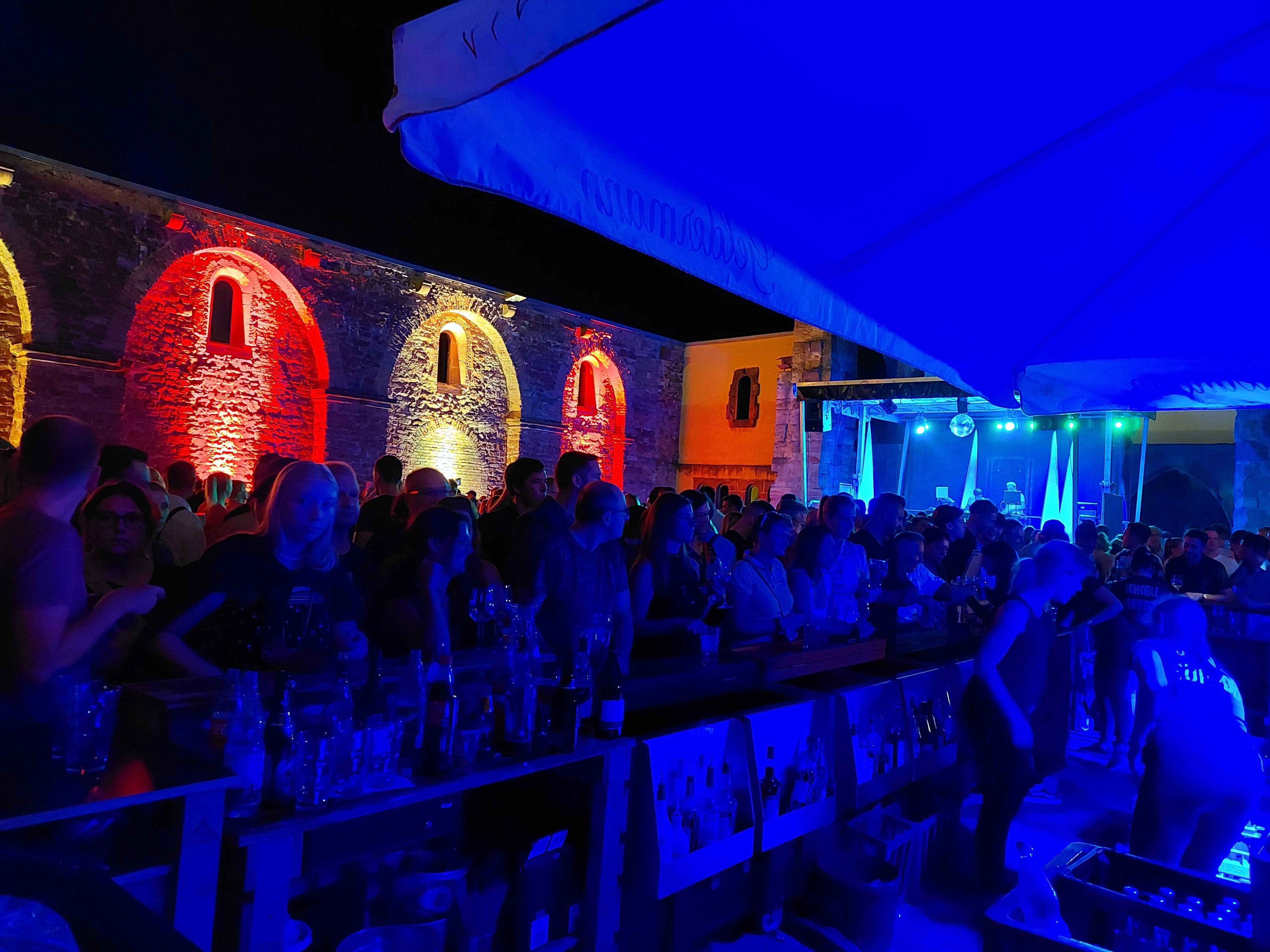 Bunt beleuchtete Mauern mit vielen Menschen.