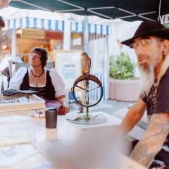 Vier Personen an einem Stand. Mittig Blick auf einen kleinen Falke.