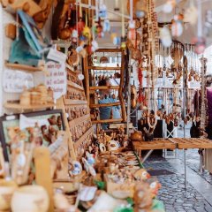 Seitlicher Blick in einem Stand mit allerlei Schmuckstücken aus Holz. Seitlich rechts laufen Personen am Stand vorbei.
