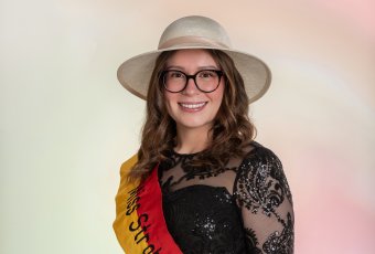 Porträtfoto einer jungen Frau mit Schärpe und Strohhut