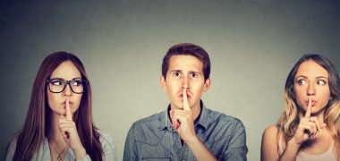 Drei Personen halten ihren Zeigefinger vor den Mund.