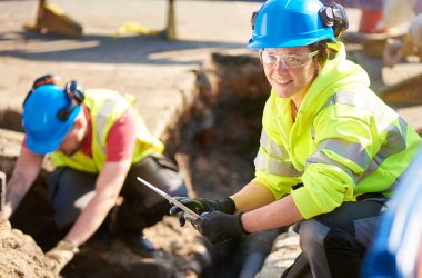 Junge Frau mit Sicherheitshelm auf Baustelle