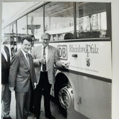 Zwei Männer vor einem Bus mit Rheinland Pfalz Banner