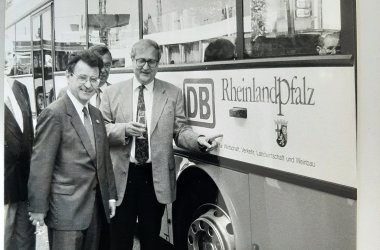 Zwei Männer vor einem Bus mit Rheinland Pfalz Banner