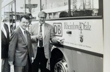 Zwei Männer vor einem Bus mit Rheinland Pfalz Banner