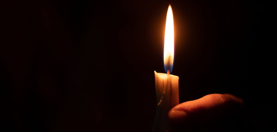 candle flame illuminates a female hand in a dark room Brennende Kerze