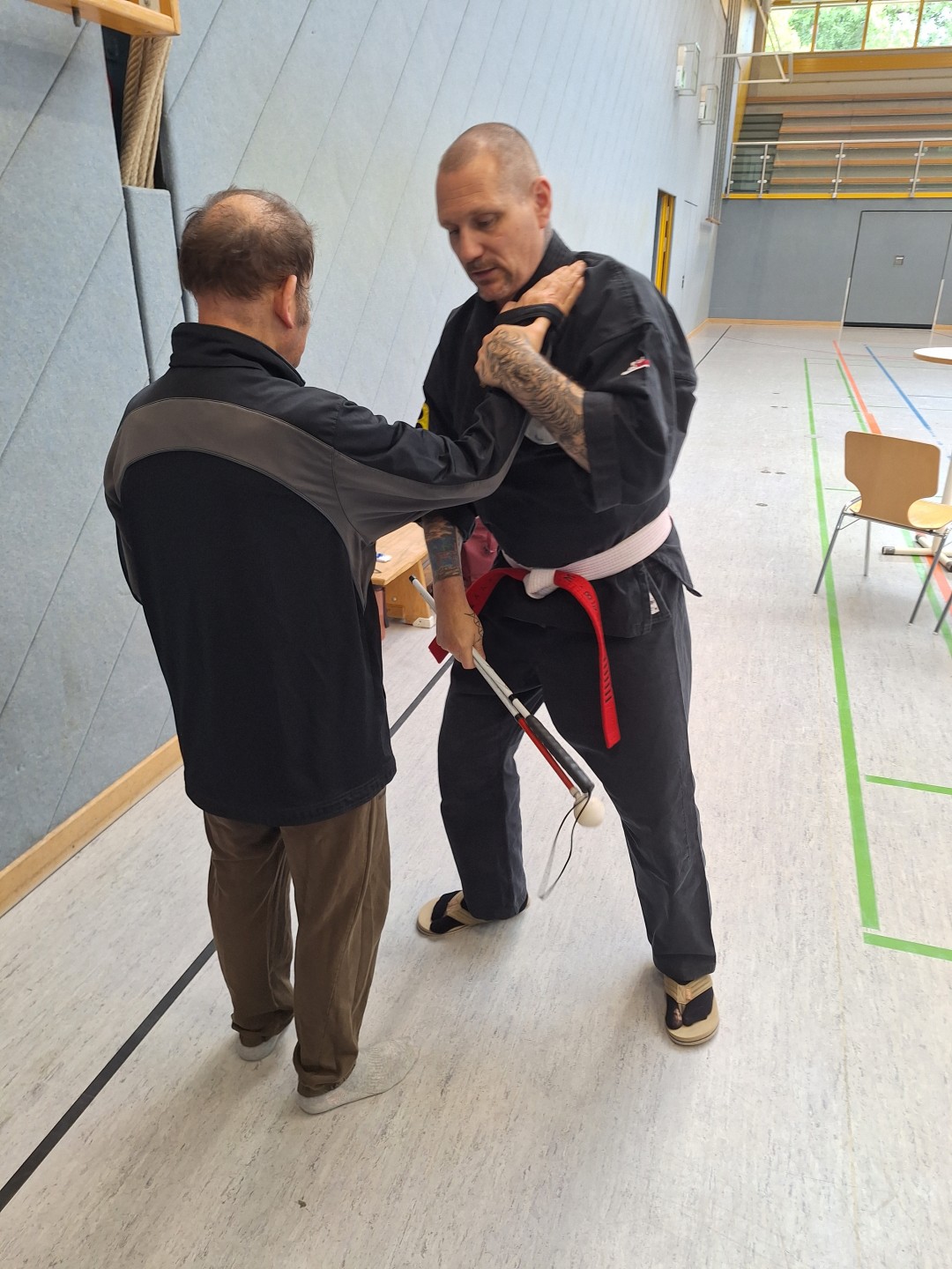 Der Trainer Marco Beyer in schwarzem Ju Jutsu Anzug hält die Hand eines der Teilnehmers.