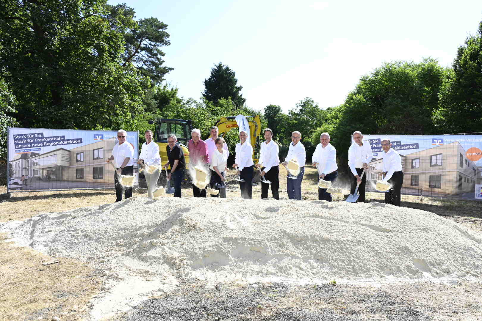 Mehrere Personen nebeneinander schaufeln Sand