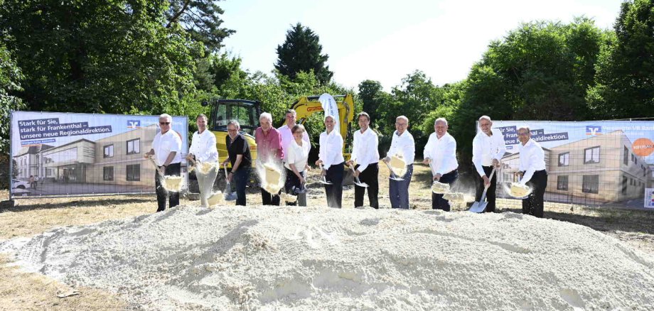 Mehrere Personen nebeneinander schaufeln Sand